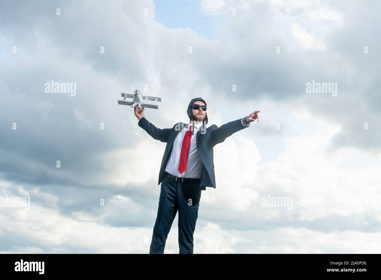 uomo d'affari in abito e cappello pilota lancia giocattolo aereo su sfondo cielo. leadership Foto Stock