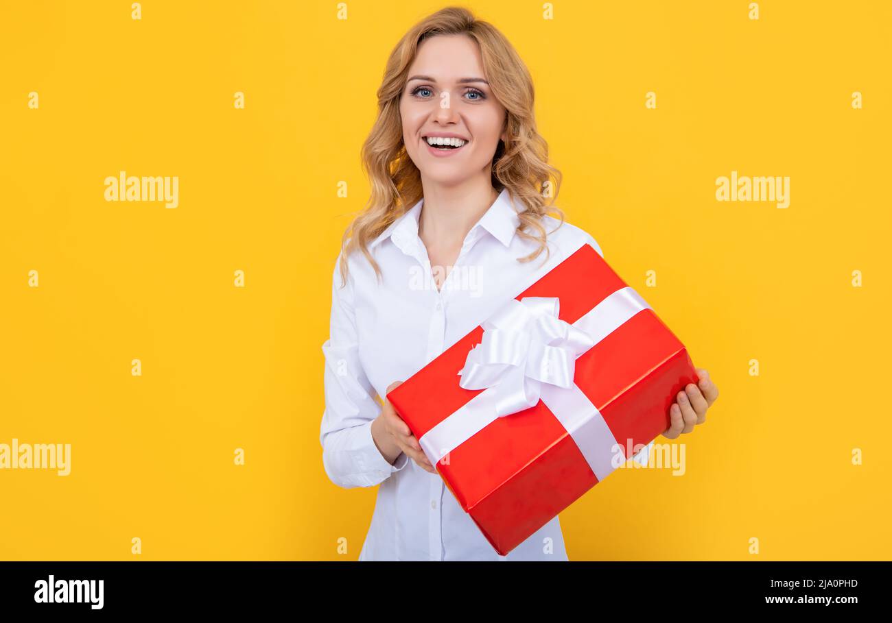 donna positiva con grande scatola presente su sfondo giallo Foto Stock