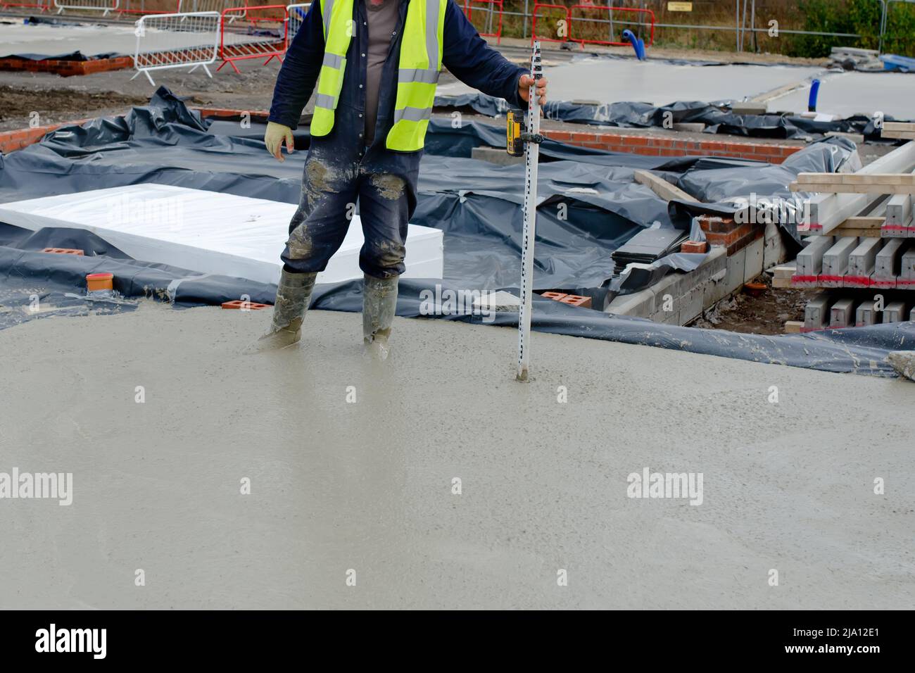 Concreter controllo livello del calcestruzzo utilizzando livello laser e personale come si versa piano terra soletta della nuova casa residenziale Foto Stock