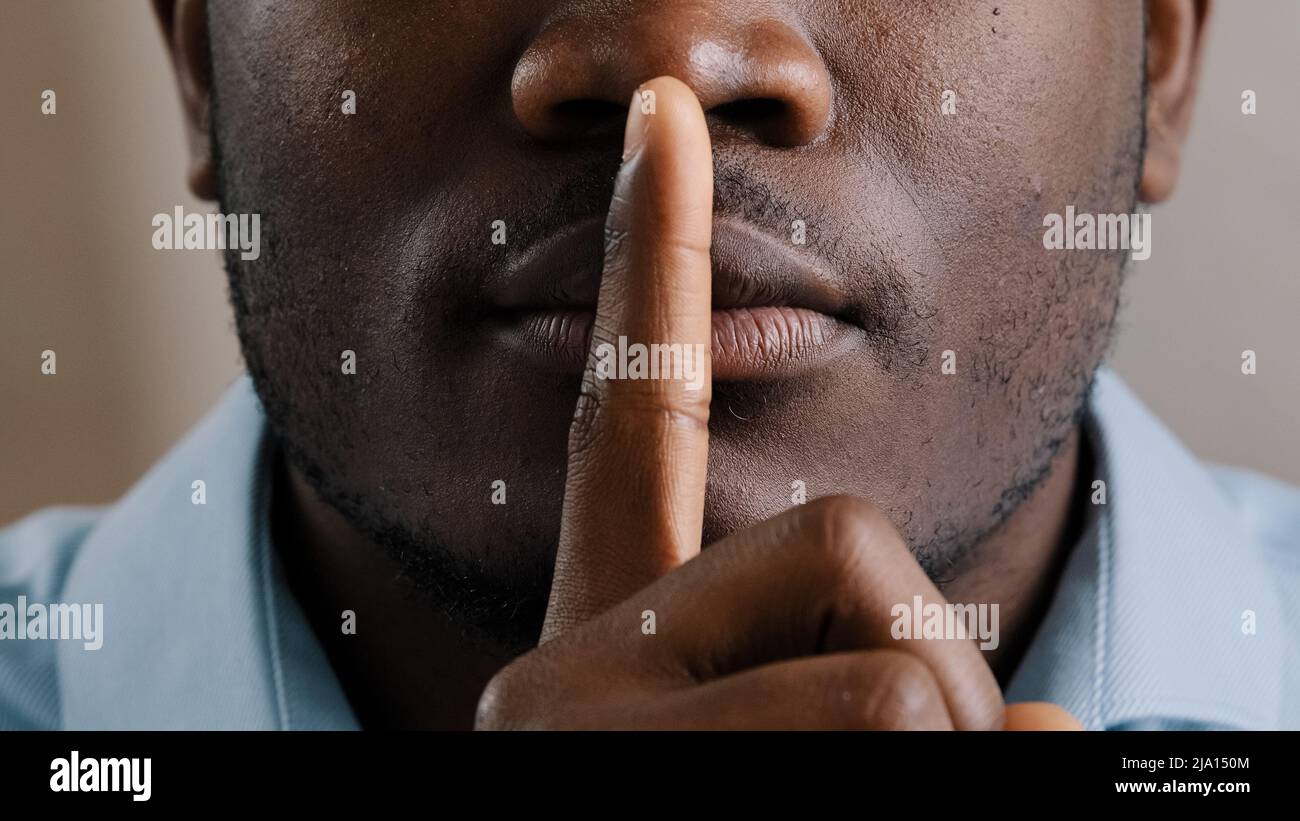 Misterioso sconosciuto maschio faccia parte afroamericano adulto uomo messo dito alle labbra chiedere di essere tranquillo fare il gesto silenzio mostrare segreto segno tenere segreto Foto Stock