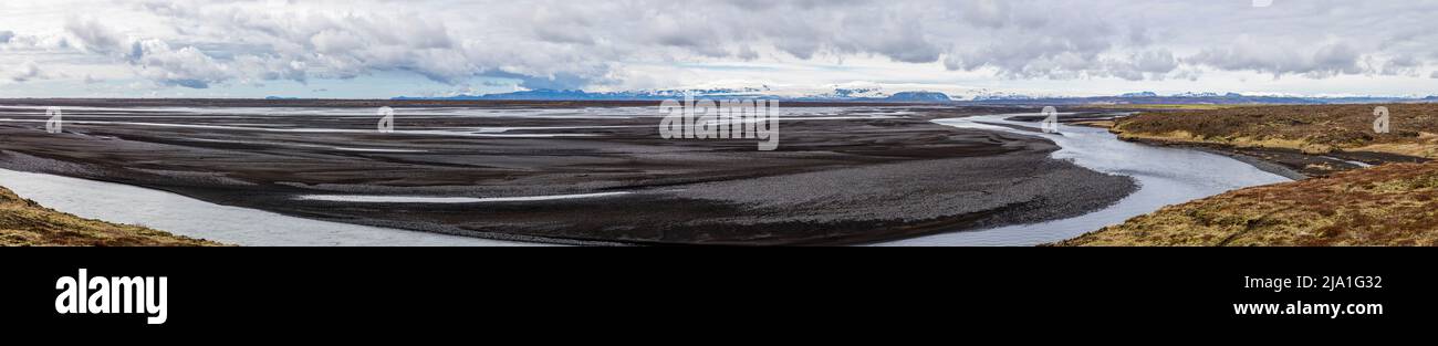 Il fiume Skaftá si snoda qui come un ampio letto fluviale intrecciato attraverso la pianura di Meðalland, Islanda; montagne ricoperte da ghiacciai si ergono all’orizzonte. L’ampio sandur alimentato dai ghiacciai è tipico della regione. Foto Stock