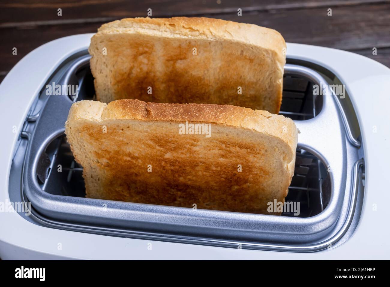 Dal tostapane fuoriescono fette di pane tostato. Cibi sani per la colazione e tecnologia di riscaldamento. Foto Stock