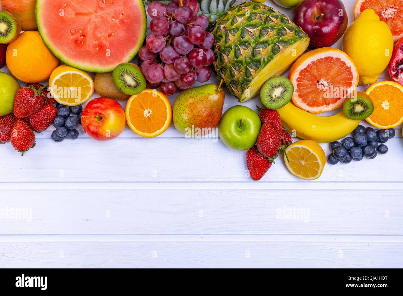 Frutta fresca assortita per un'alimentazione sana. Cocomero, ananas, mela, pera, fragola, kiwi, limone, arancia, uva, mirtillo, melograno, mango, b Foto Stock