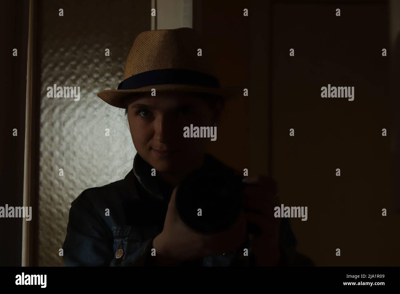 Defocus giovane donna prendere la fotografia in riflessione specchio. Donna millenaria in cappello. Ritratto nero scuro. Salute mentale. Narcisismo. Fuori fuoco. Foto Stock