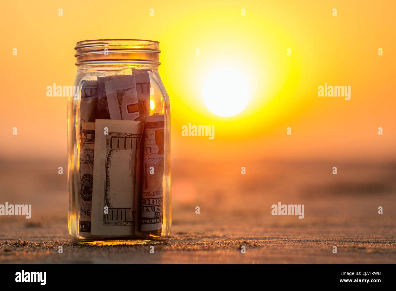 un vaso di vetro con monete e bollette sulla spiaggia. il concetto di accumulo di denaro per i viaggi Foto Stock
