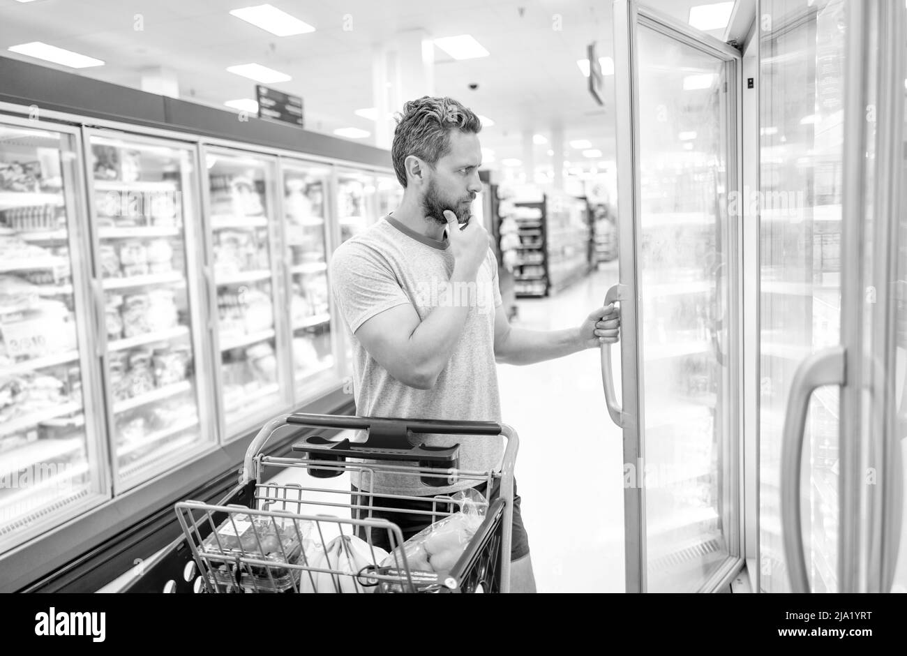 uomo ponderante con carrello di acquisto di cibo a drogheria, ipermercato Foto Stock