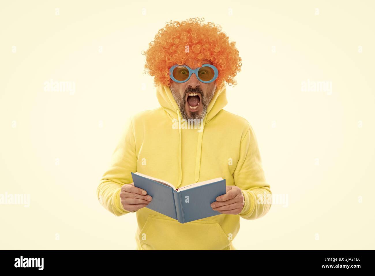 Geeky bibliophile in funky wig tenere la bocca aperta lettura libro della scuola, biblioteca Foto Stock