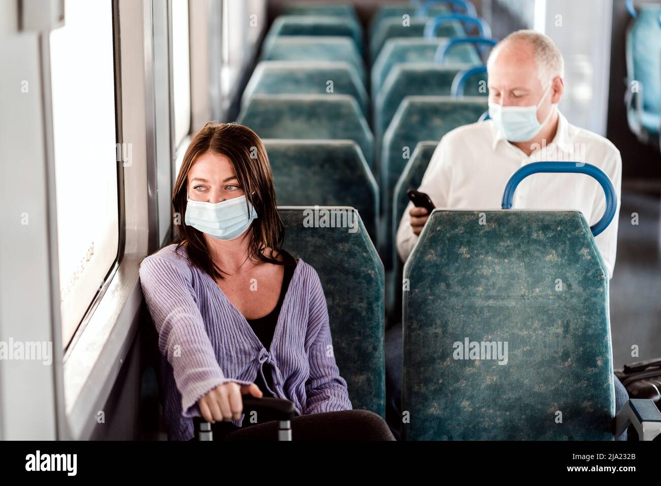 Passeggeri seri in maschere protettive durante il viaggio di un giorno in treno Foto Stock