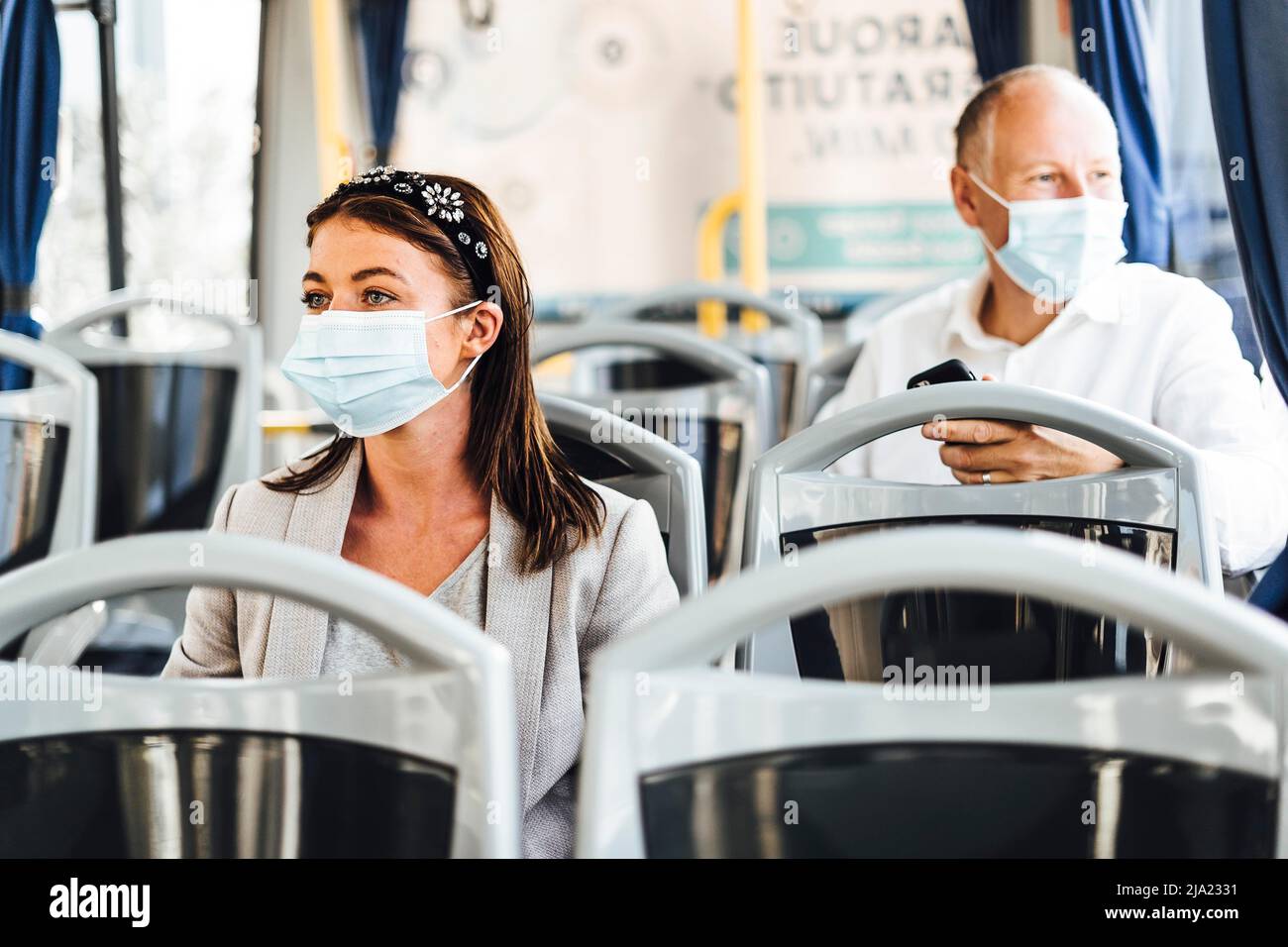 Viaggiatori che indossano maschere protettive che viaggiano con autobus pubblico Foto Stock