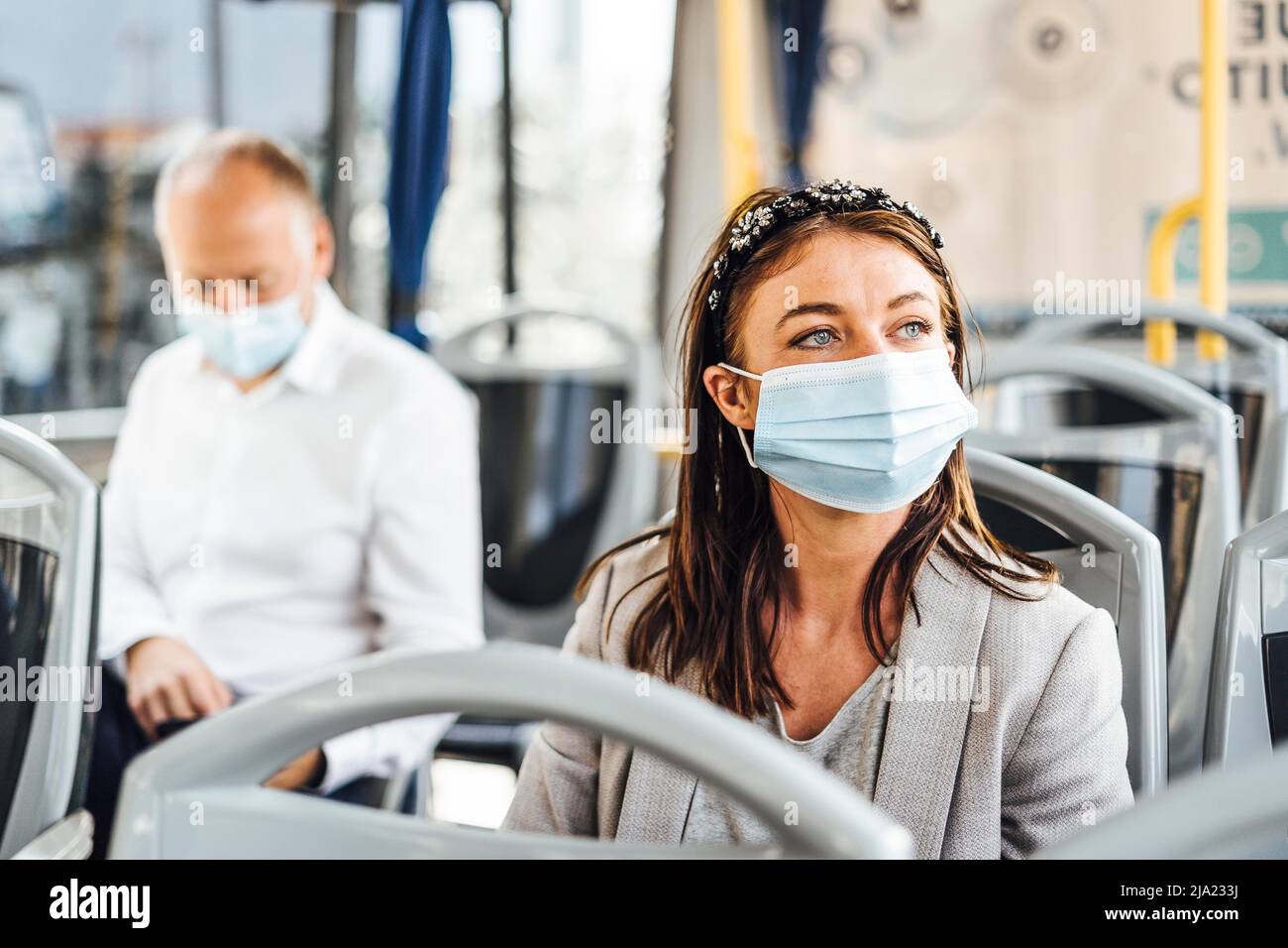 Viaggiatori che indossano maschere protettive che viaggiano con autobus pubblico Foto Stock