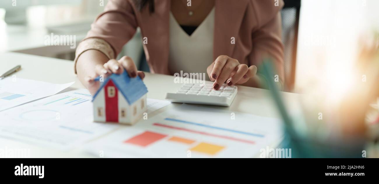 Businesswoman che lavora facendo le finanze e il costo di calcolo dell'investimento di bene immobile mentre sta firmando al contratto, approvazione di prestito ipotecario di concetto Foto Stock