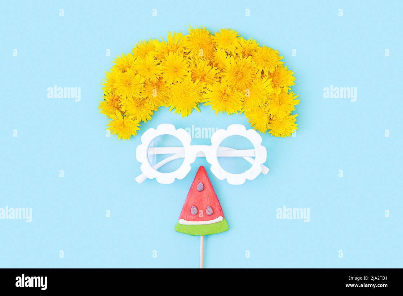 Concetto creativo e luminoso d'estate. Faccia astratta di un touristmade con vetri, fiori, e lollipop watermelon su sfondo blu. Vista dall'alto, disposizione piatta. Foto Stock