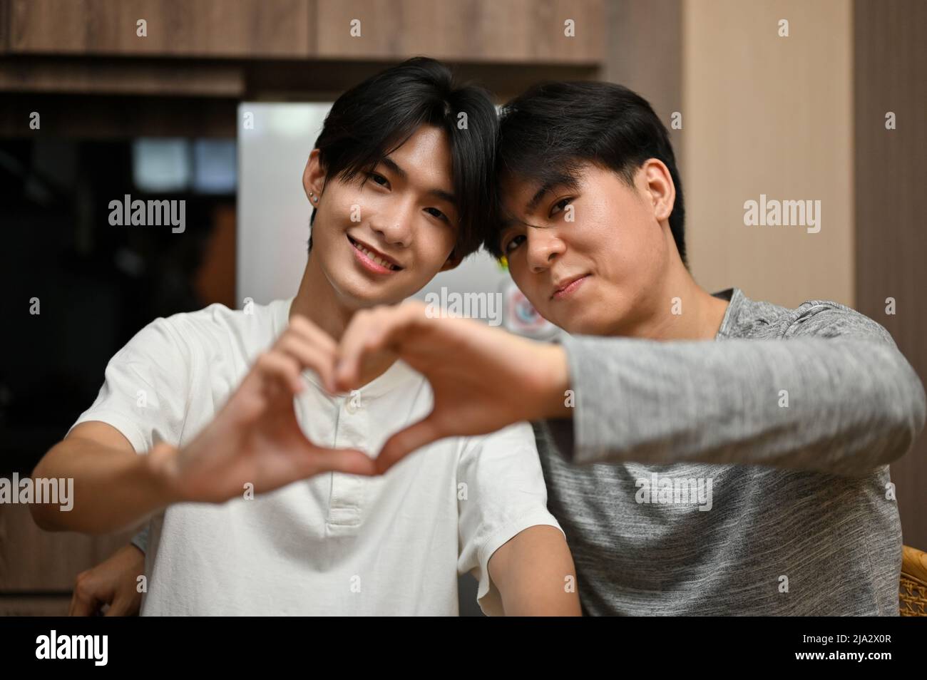 Un'amorevole coppia di uomini gay asiatici adolescenti che fanno il cuore forma con le mani. LGBT che mostra un segno del cuore: Amore, diversità e concetto di uguaglianza Foto Stock