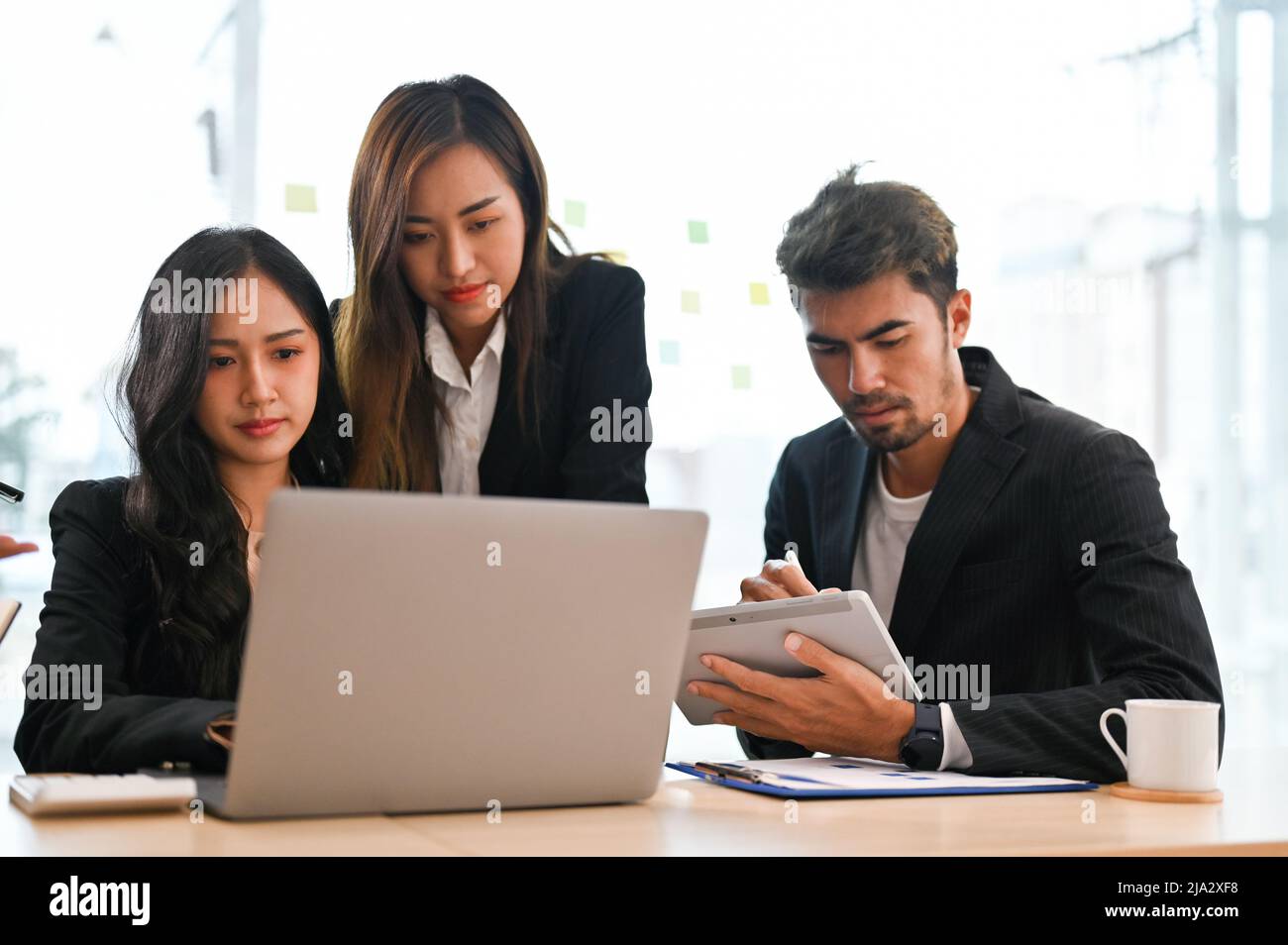 Un gruppo di imprenditori asiatici professionisti che hanno un incontro informale per brainstorm il loro progetto insieme in ufficio. Foto Stock