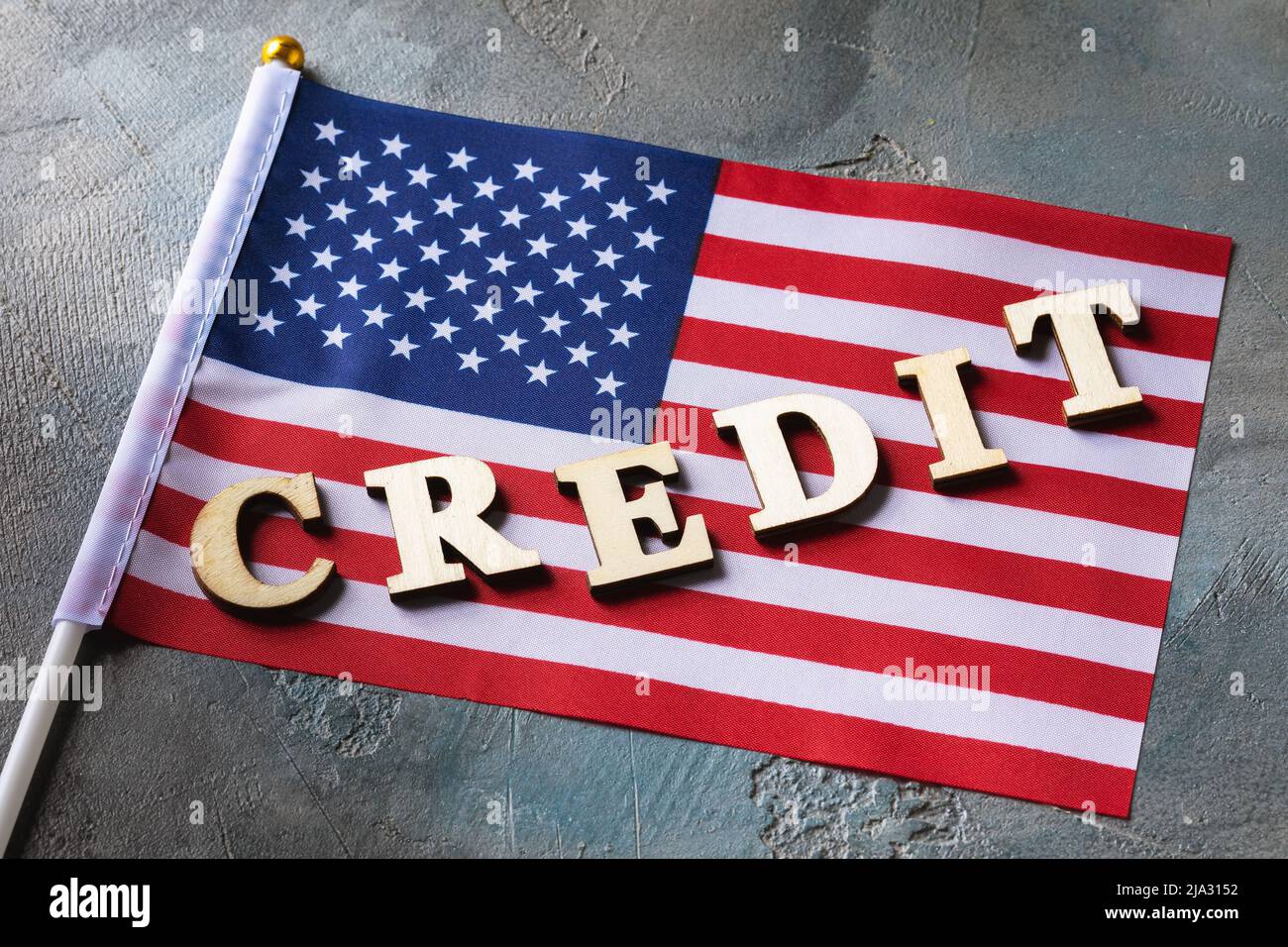 Testo delle lettere in legno e bandiera americana su sfondo astratto, concetto di credito dagli Stati Uniti d'America Foto Stock