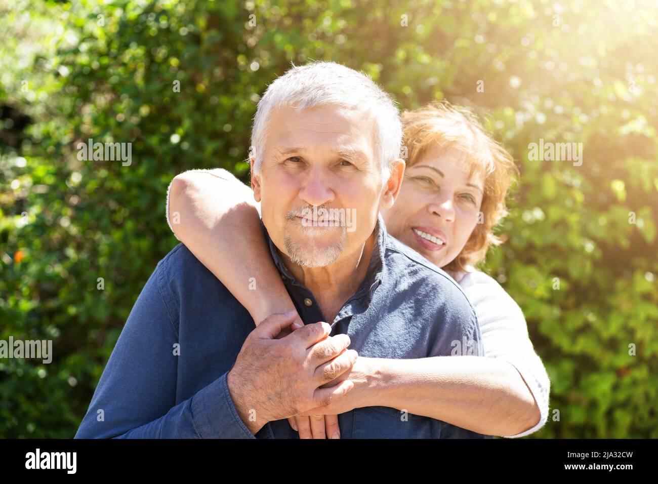 Ritratto di donna felice abbracciando il marito da dietro Foto Stock