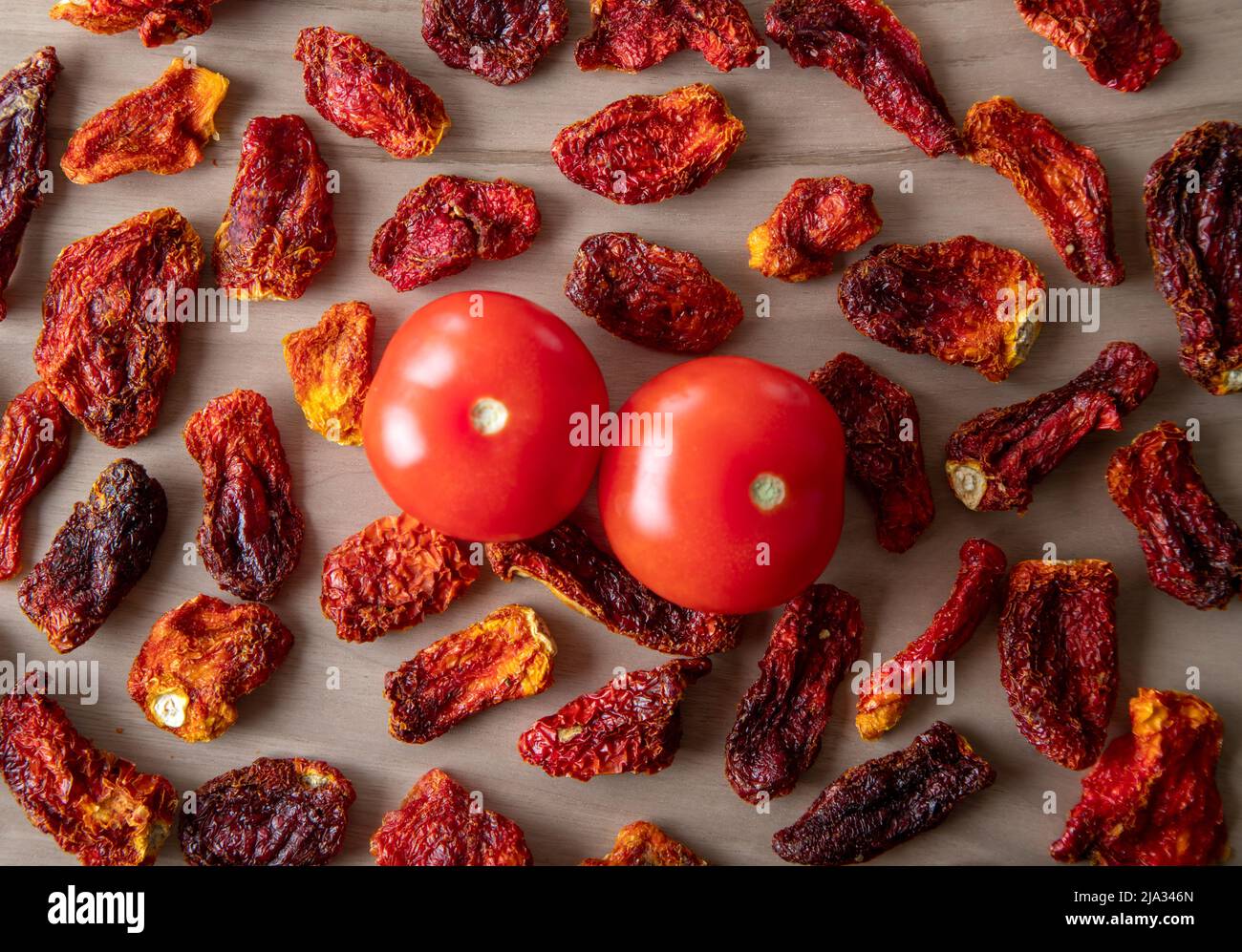 Pomodori freschi e pomodori secchi con fondo in legno Foto Stock