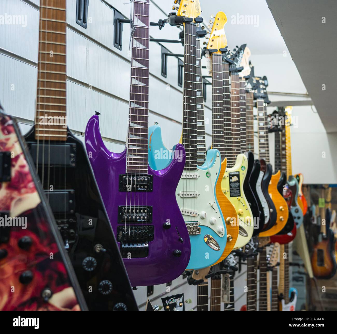 Una collezione di chitarre elettriche colorate in mostra presso un negozio di musica. Foto Stock