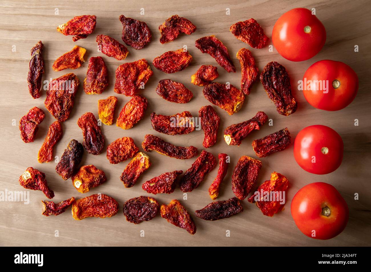 Pomodori freschi e pomodori secchi con fondo in legno Foto Stock
