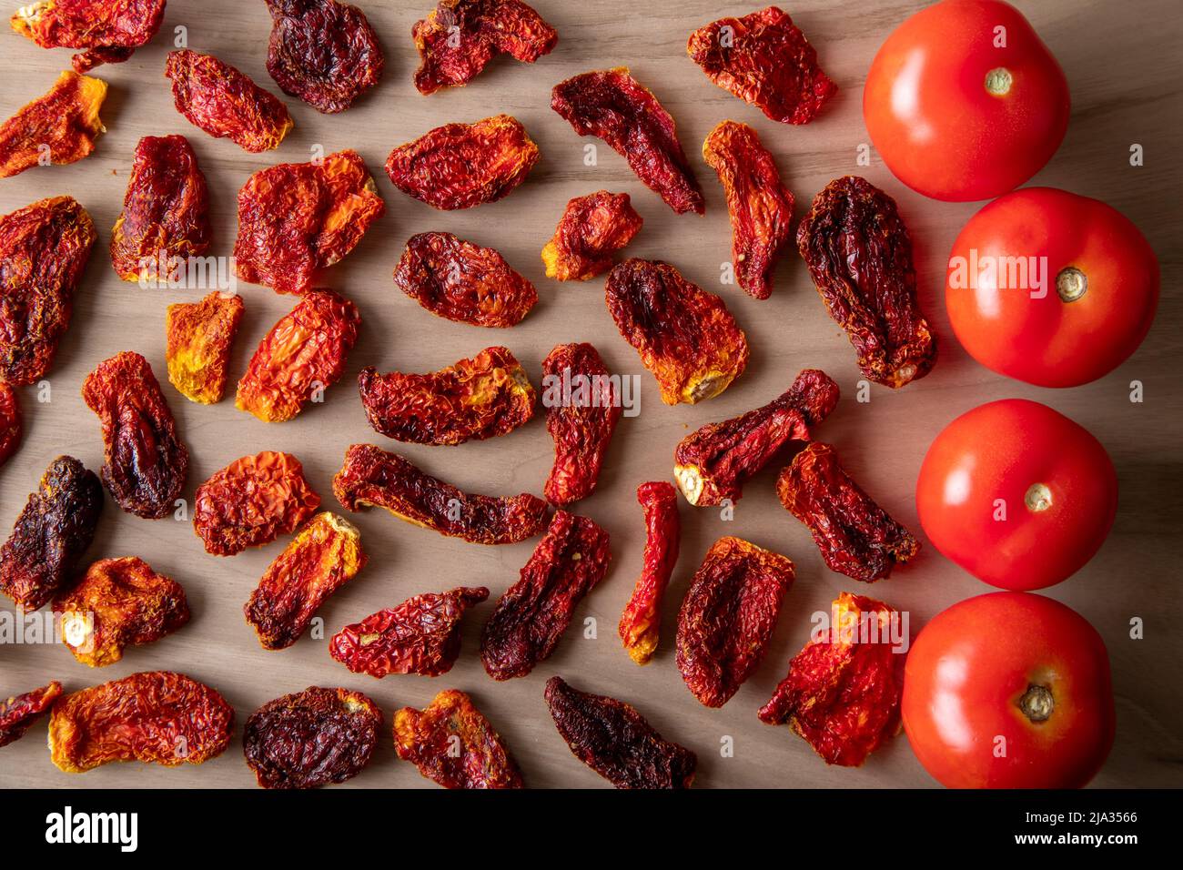 Pomodori freschi e pomodori secchi con fondo in legno Foto Stock