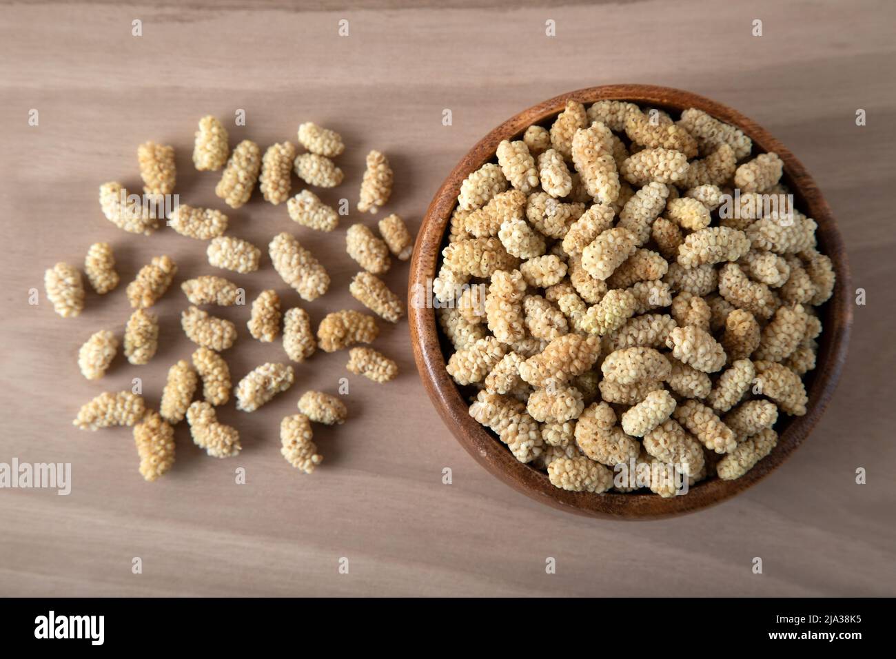Ciotola piena di gelso secco su sfondo di legno Foto Stock