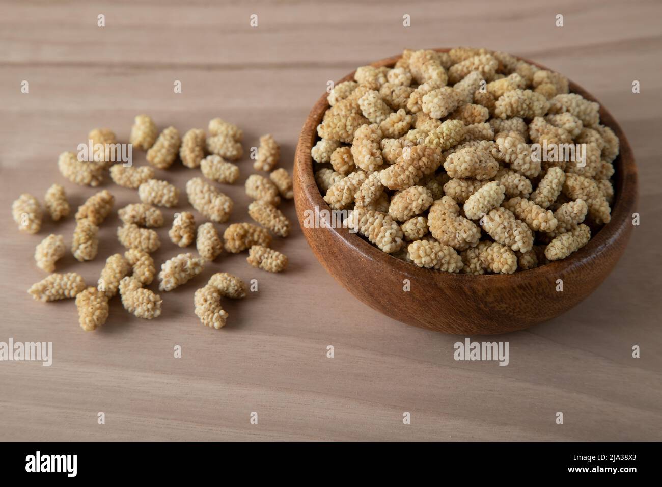 Ciotola piena di gelso secco su sfondo di legno Foto Stock