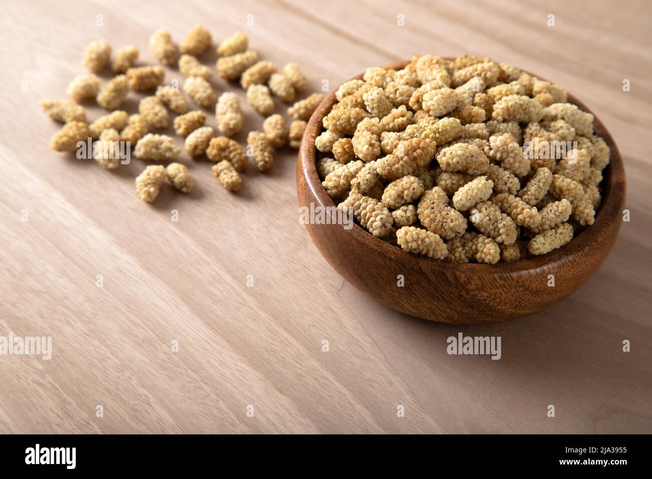 Ciotola piena di gelso secco su sfondo di legno Foto Stock