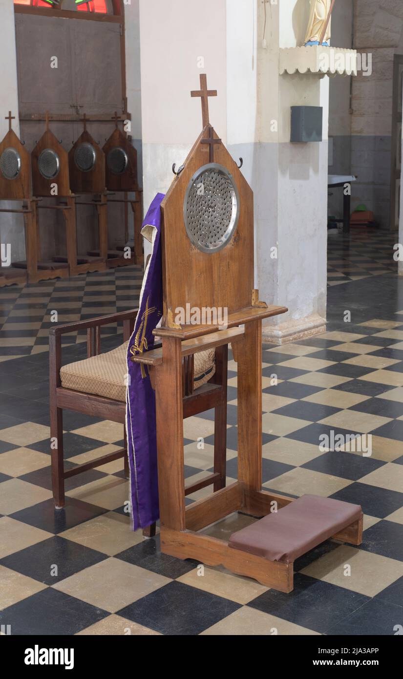 Una sedia confessionale e panca di ginocchio all'interno di una chiesa nel sud dell'India. Foto Stock