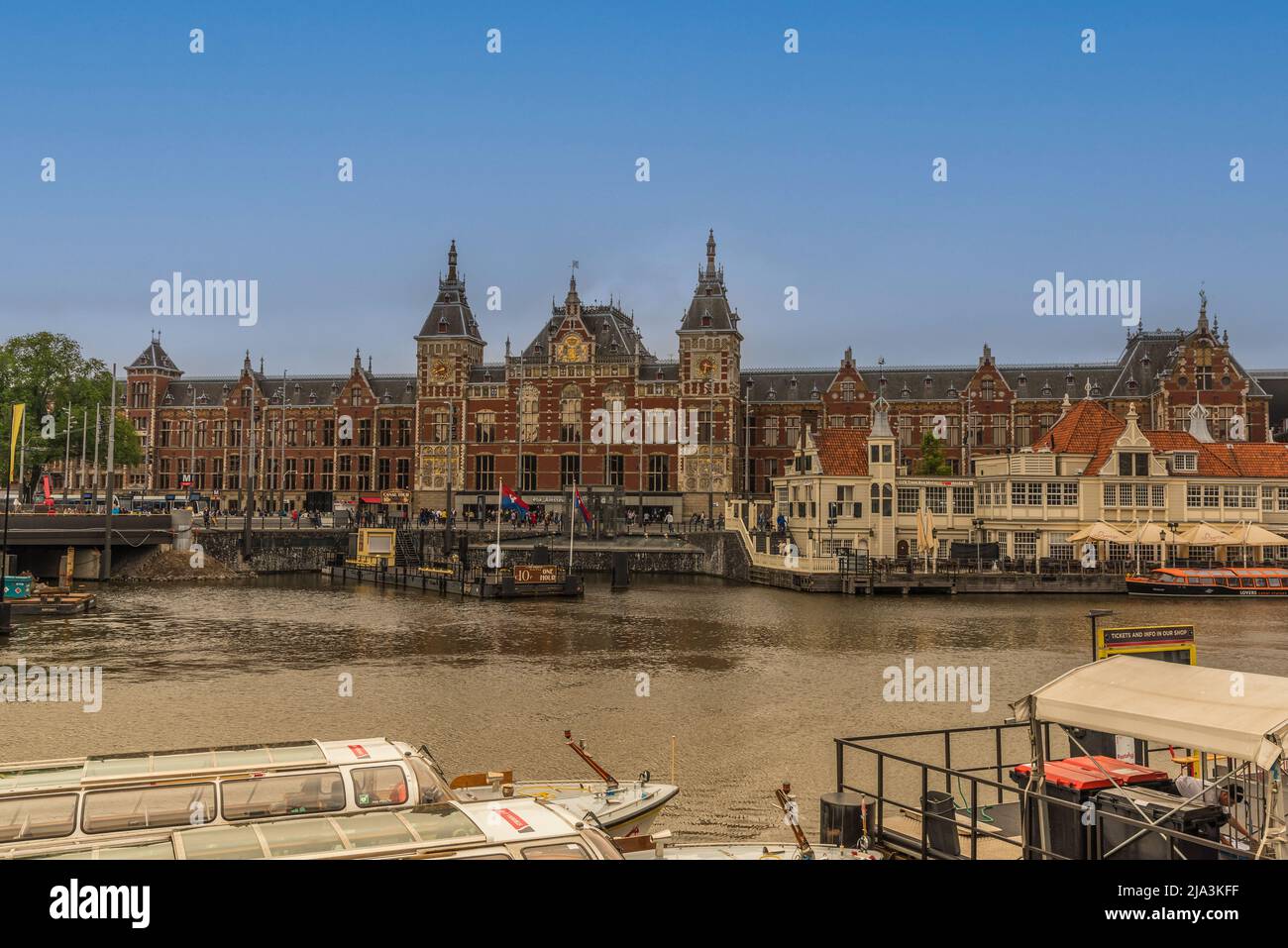 Amsterdam, Paesi Bassi, maggio 2022. La stazione centrale di Amsterdam e le barche da crociera sul canale presso il Damrak di Amsterdam. Foto di alta qualità Foto Stock