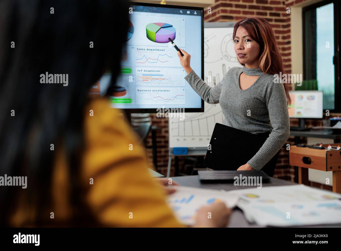 Donna d'affari seduta accanto al monitor mostrando grafici di gestione brainstorming idee per il progetto di partnership. Team di marketing che discute della strategia aziendale che lavora in startup Office. Ambiente di lavoro moderno Foto Stock