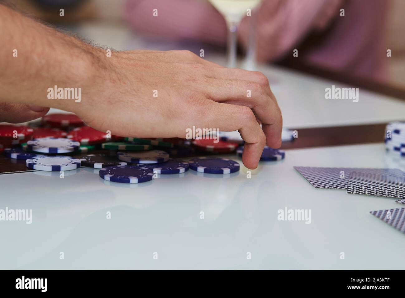 Giocatore in gioco di poker con chip, carte sul tavolo con riflessione. Godendo il momento con gli amici, detox digitale. Fotografia di stile di vita. Momento candida. Messa a fuoco selettiva Foto Stock