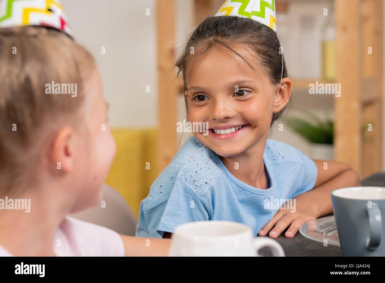 Ragazze carine seduti al tavolo e bere il tè, mescolando farina e uova in una ciotola d'acciaio di fronte alla macchina fotografica in cucina ambiente Foto Stock