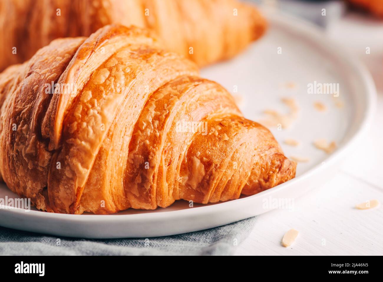 Piatto con croissant freschi su tavolo di legno bianco. Foto Stock