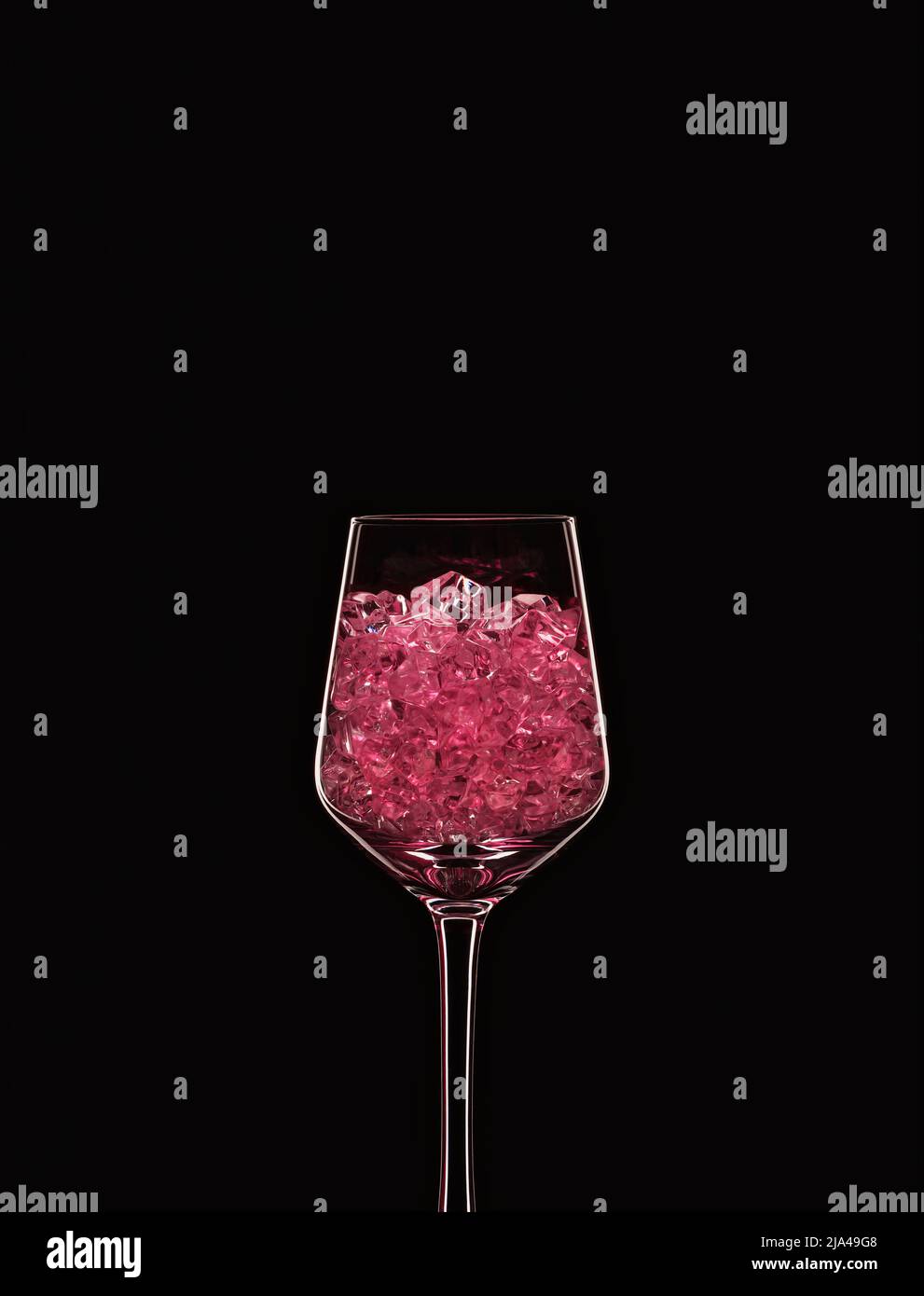Bicchiere da vino riempito con cristalli rosa trasparenti retroilluminati e isolati su sfondo nero. Concetto di vetreria per bevande. Spazio di copia. Foto Stock