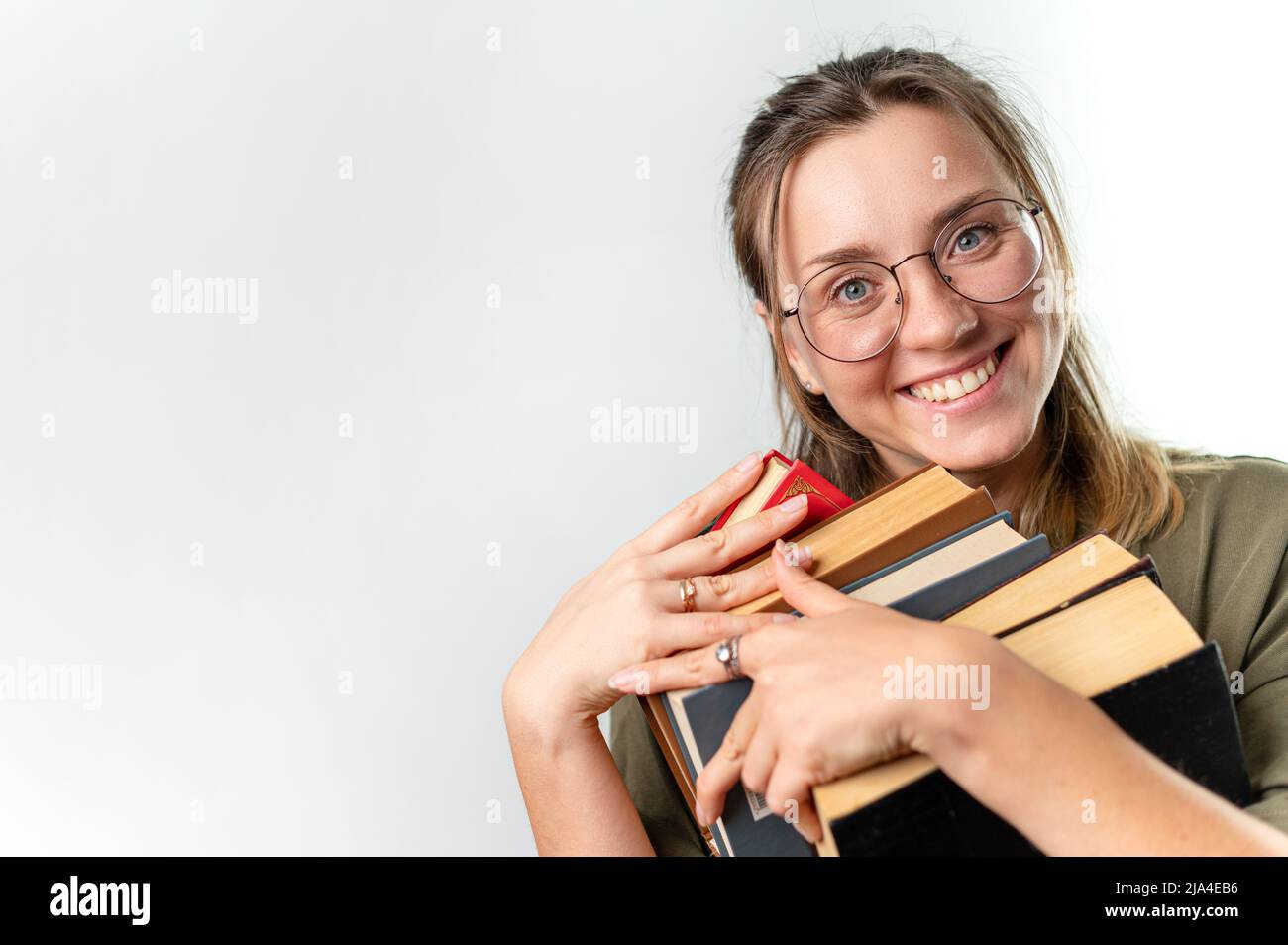 Giovane eccitata donna sorridente studentessa che tiene libri dal suo volto, sfondo bianco Foto Stock