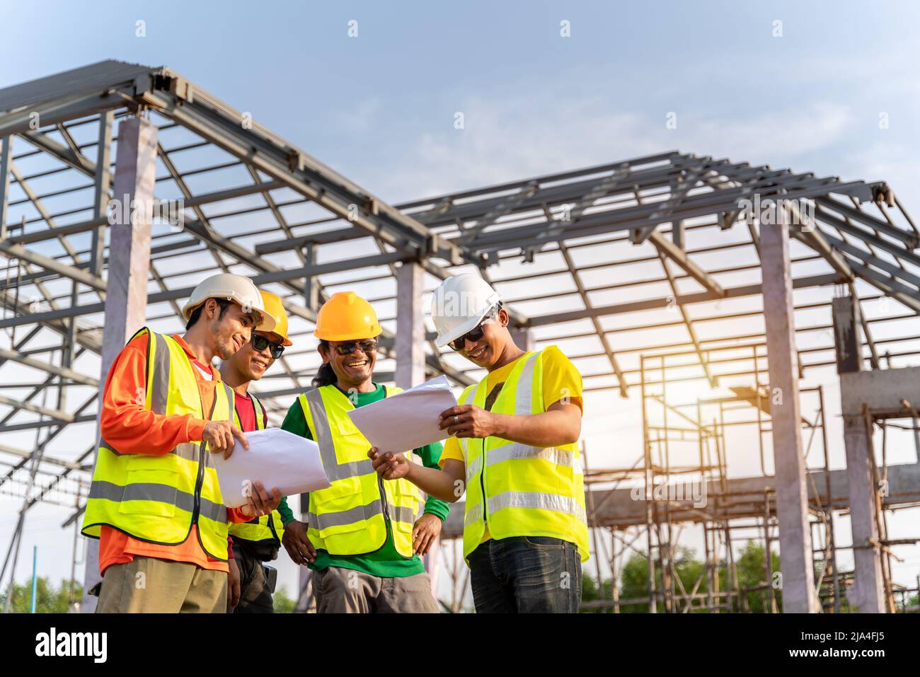 4 lavoratori del cantiere, tecnici dell'architetto tecnico utilizzano la stampa blu Planing insieme prima di iniziare il lavoro. Struttura del tetto in acciaio non Foto Stock