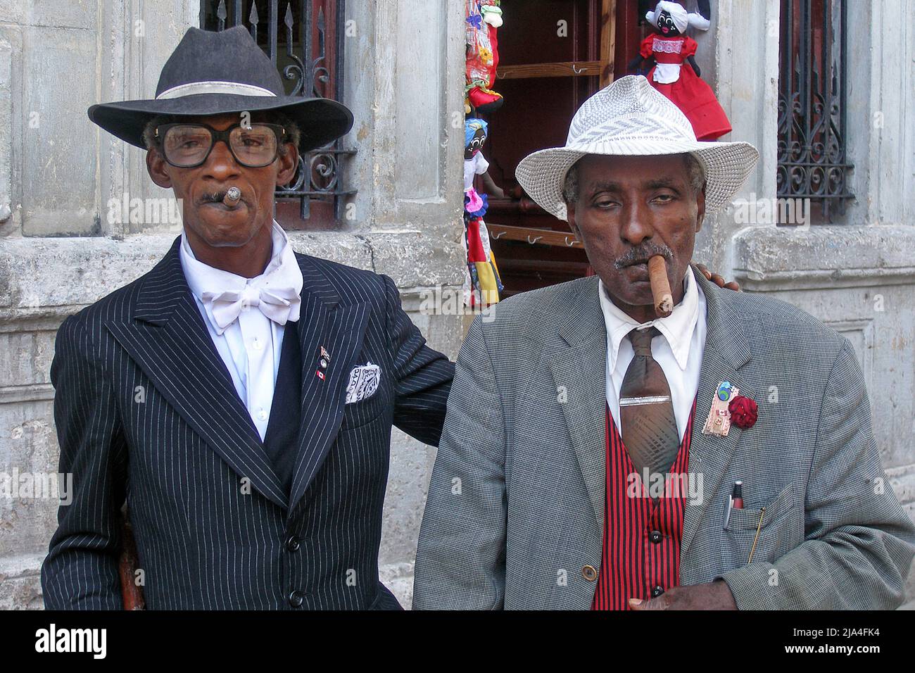 Due uomini cubani ben vestiti e sambuco fumano sigari, Plaza Cattedrale, storico centro storico di l'Avana, Cuba, Caraibi Foto Stock