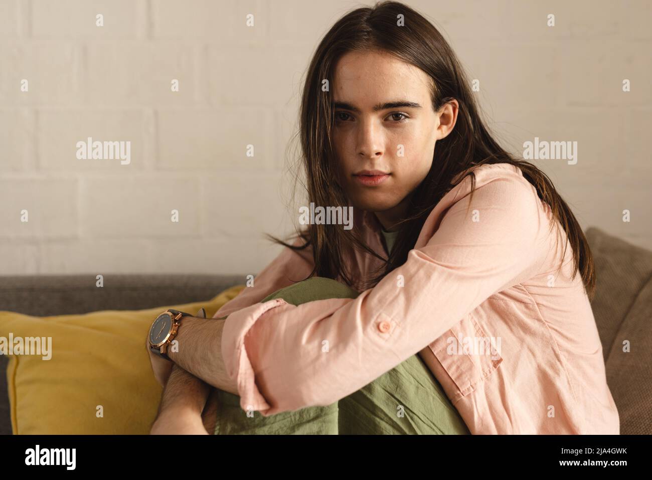 Ritratto di trans donna non binaria seduta sul divano a casa Foto Stock
