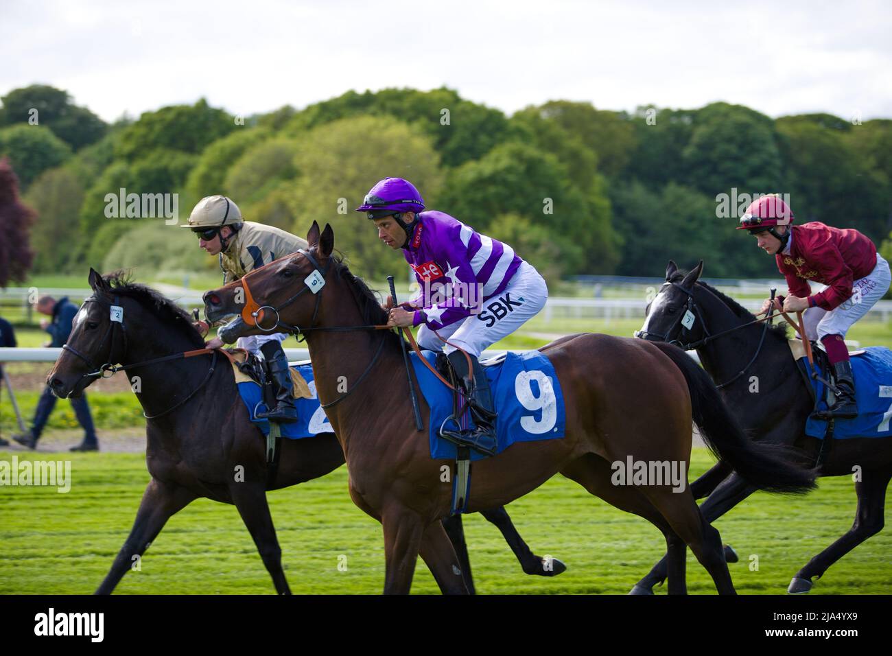 Jockeys galoppando verso le porte di partenza prima della Frank Whittle Partnership ebfstallions.com Maiden Stakes (gara GBB) a York. Foto Stock