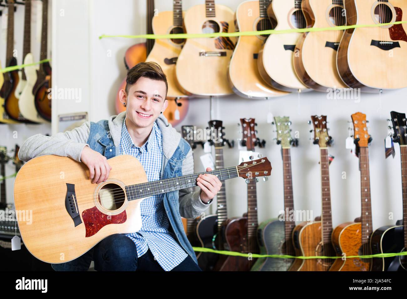 Teenager che sceglie chitarre acustiche Foto Stock