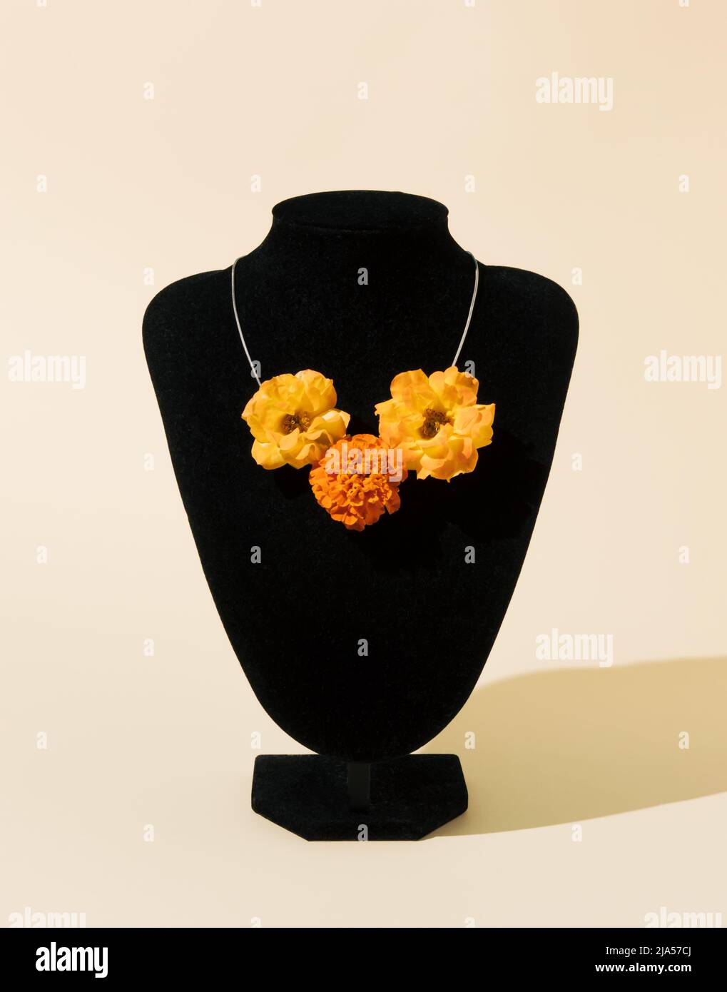 Collana creativa ed elegante fatta di fiori gialli su sfondo beige. Moderno concetto minimalista. Composizione estiva. Foto Stock