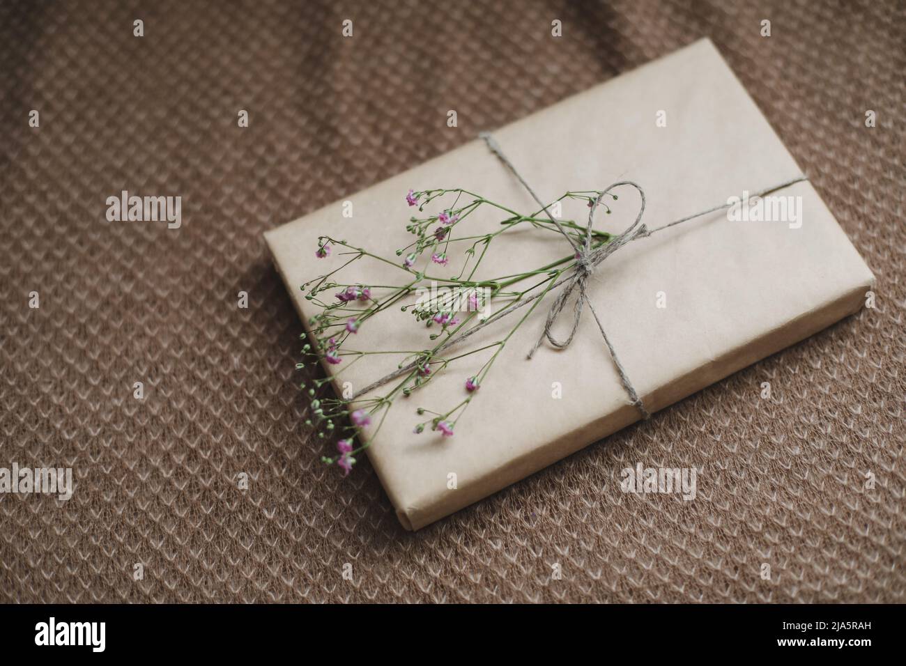 una scatola regalo in carta artigianale decorata con un fiore Foto Stock