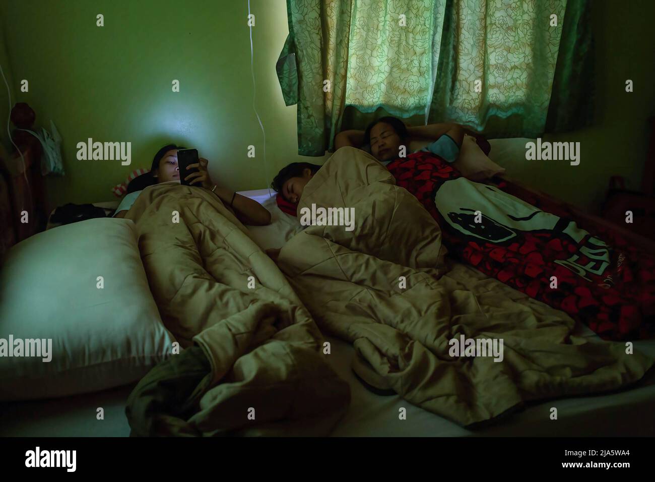 Nutthaya Namongkol, meglio conosciuto come PEEM guarda nel suo telefono mentre riposa con altri combattenti in una camera d'albergo. Anni fa vedere le donne in un anello di combattimento (Muay Thai) in Thailandia era quasi inaudito di, a meno che non fosse in una lotta cerimoniale nel tempio locale durante la stagione festiva. Oggi le cose stanno cambiando e sempre più donne si uniscono allo sport. La città di Chiang mai è l'epicentro di questo cambiamento con il supporto di un promotore locale che vede lo sport come un modo per promuovere l'uguaglianza, e il crescente interesse per lo sport da parte degli stranieri che si incatenano nella città. In alcune palestre Muay Thai, Wome Foto Stock