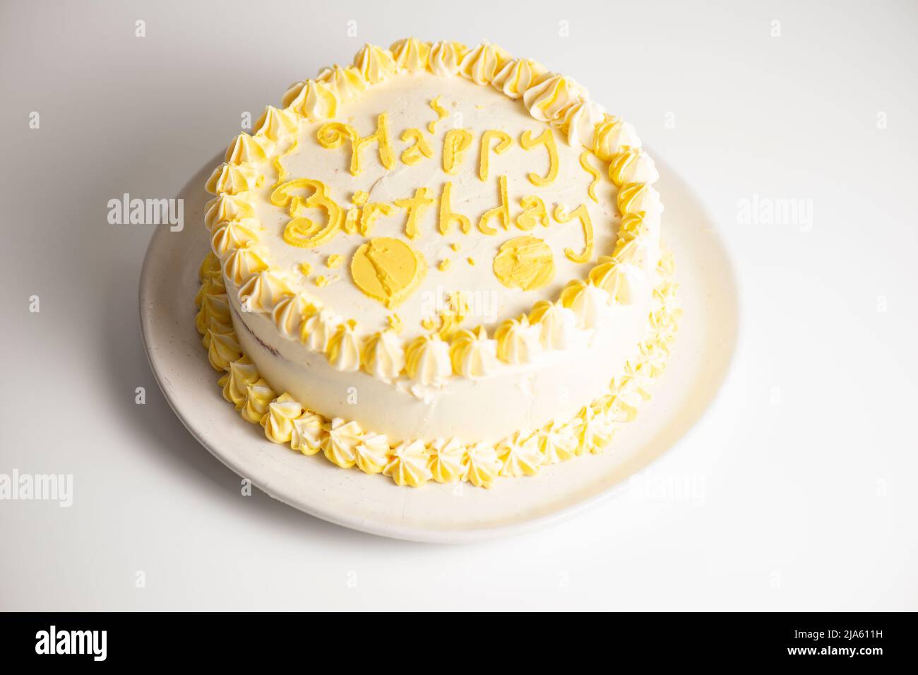 Torta in spugna al limone Happy Birthday con glassa decorativa gialla. Foto Stock