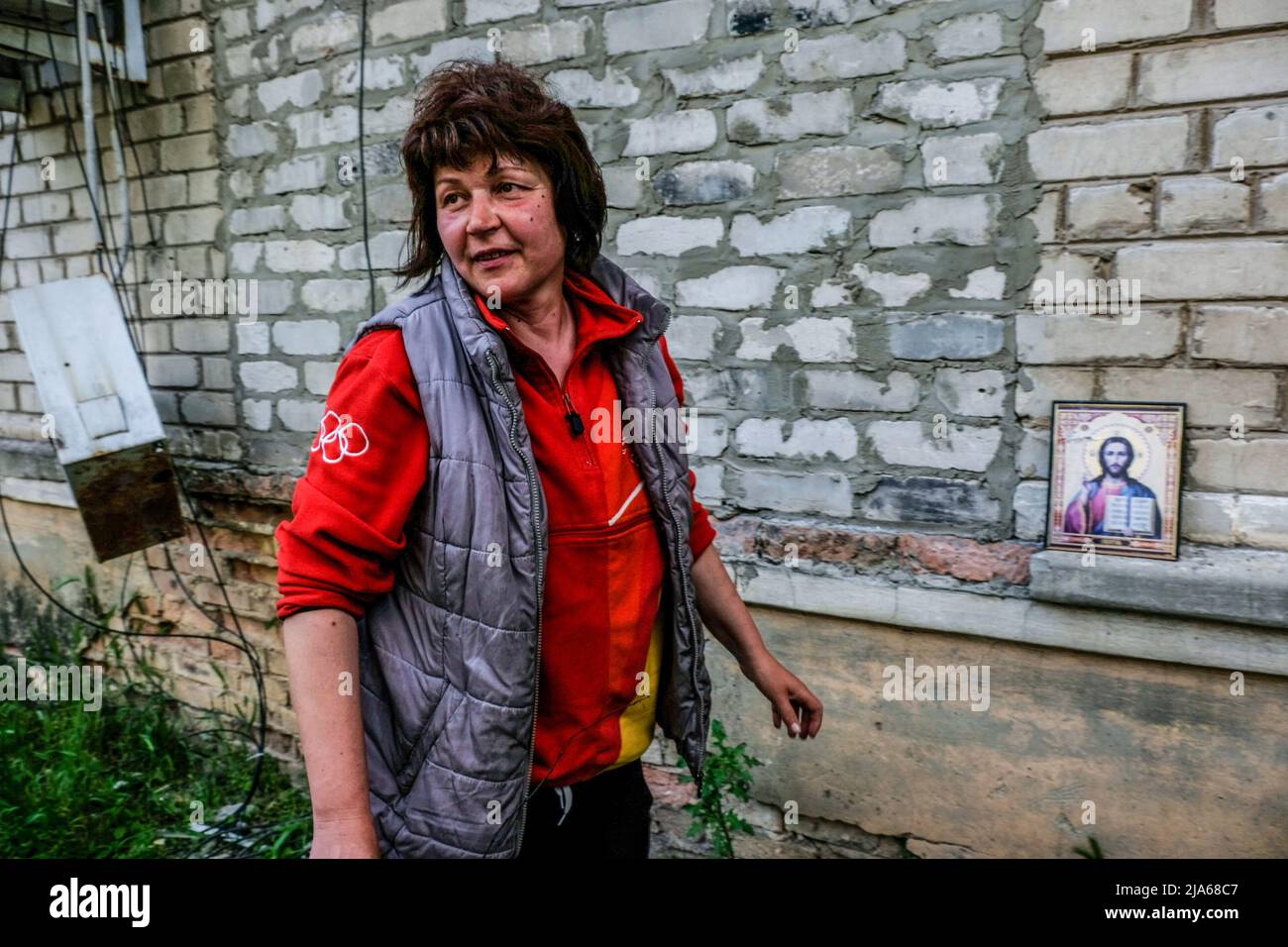 Verkhnokmayanske, Ucraina. 27th maggio 2022. Una donna mette l'immagine di Gesù Cristo su un muro di un edificio distrutto. Verkhnokmayanske è una piccola città della regione di Donetsk. La città soffre di una carenza di cibo e medicinali, gas, acqua e interruzione dell'elettricità. Di conseguenza, la prima linea si avvicina ogni giorno alla città e la maggior parte dei civili fugge. (Foto di Rick Mave/SOPA Images/Sipa USA) Credit: Sipa USA/Alamy Live News Foto Stock