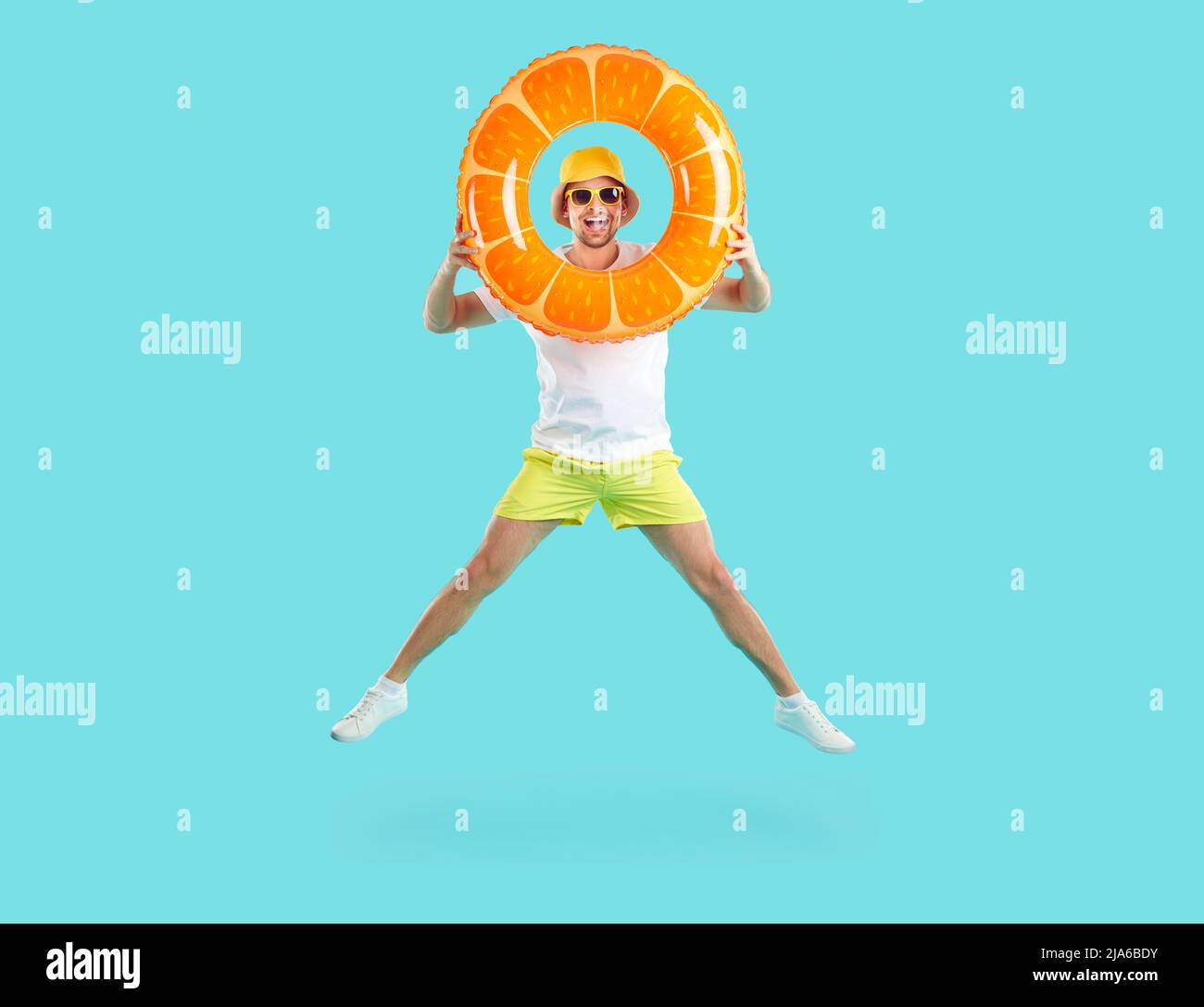 Allegro uomo divertente guardando attraverso cerchio gonfiabile rimbalzare con lui su sfondo azzurro chiaro. Foto Stock
