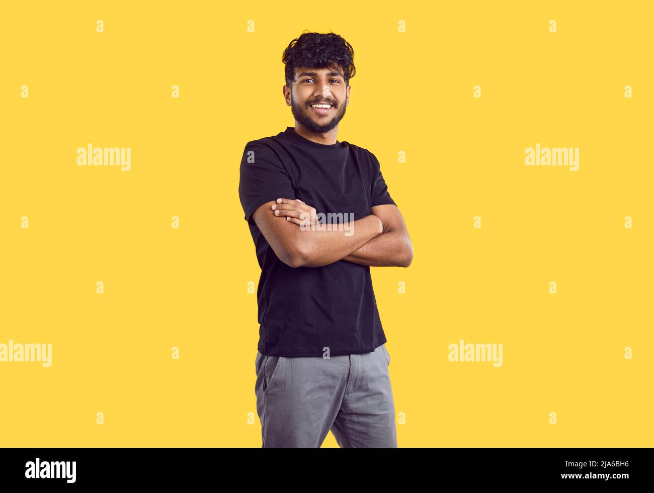 Felice bel giovane uomo indiano in abiti casual in piedi isolato su sfondo giallo Foto Stock