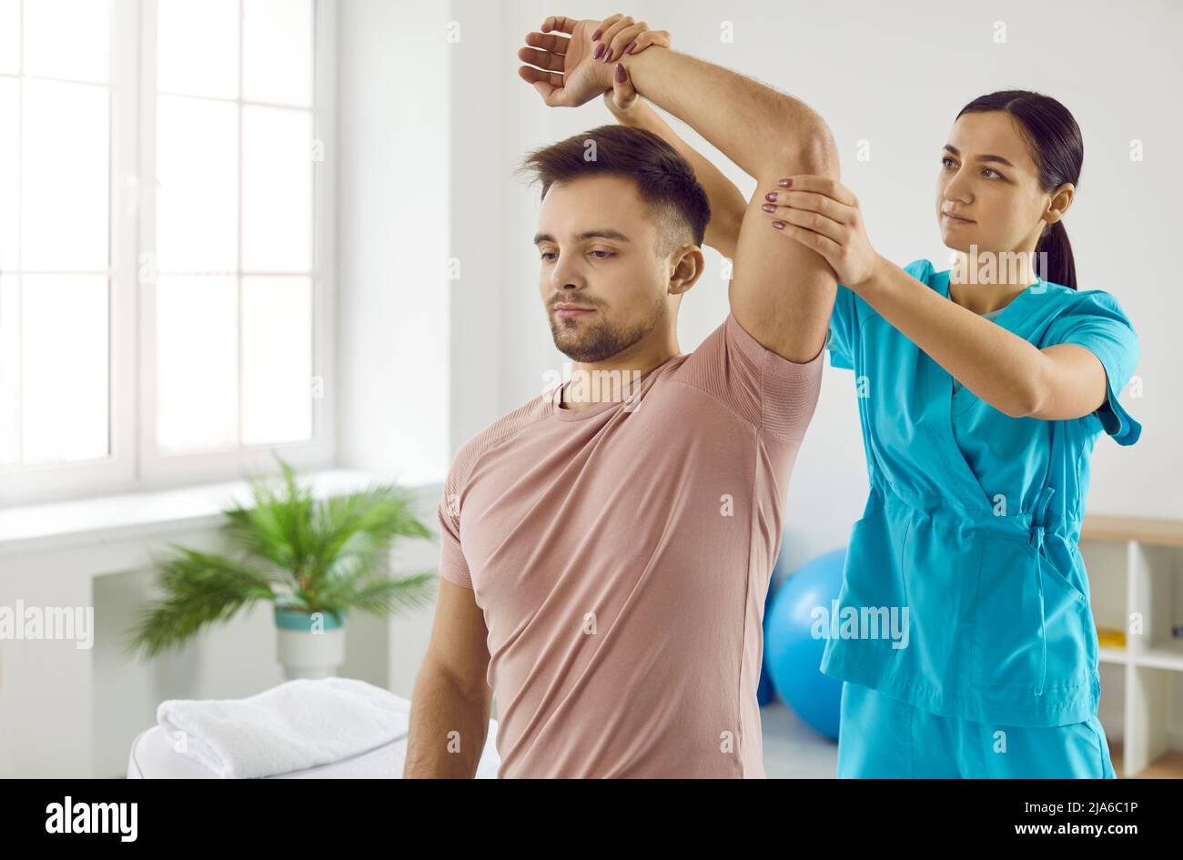 Il terapista femminile aiuta il paziente con la riabilitazione del braccio Foto Stock
