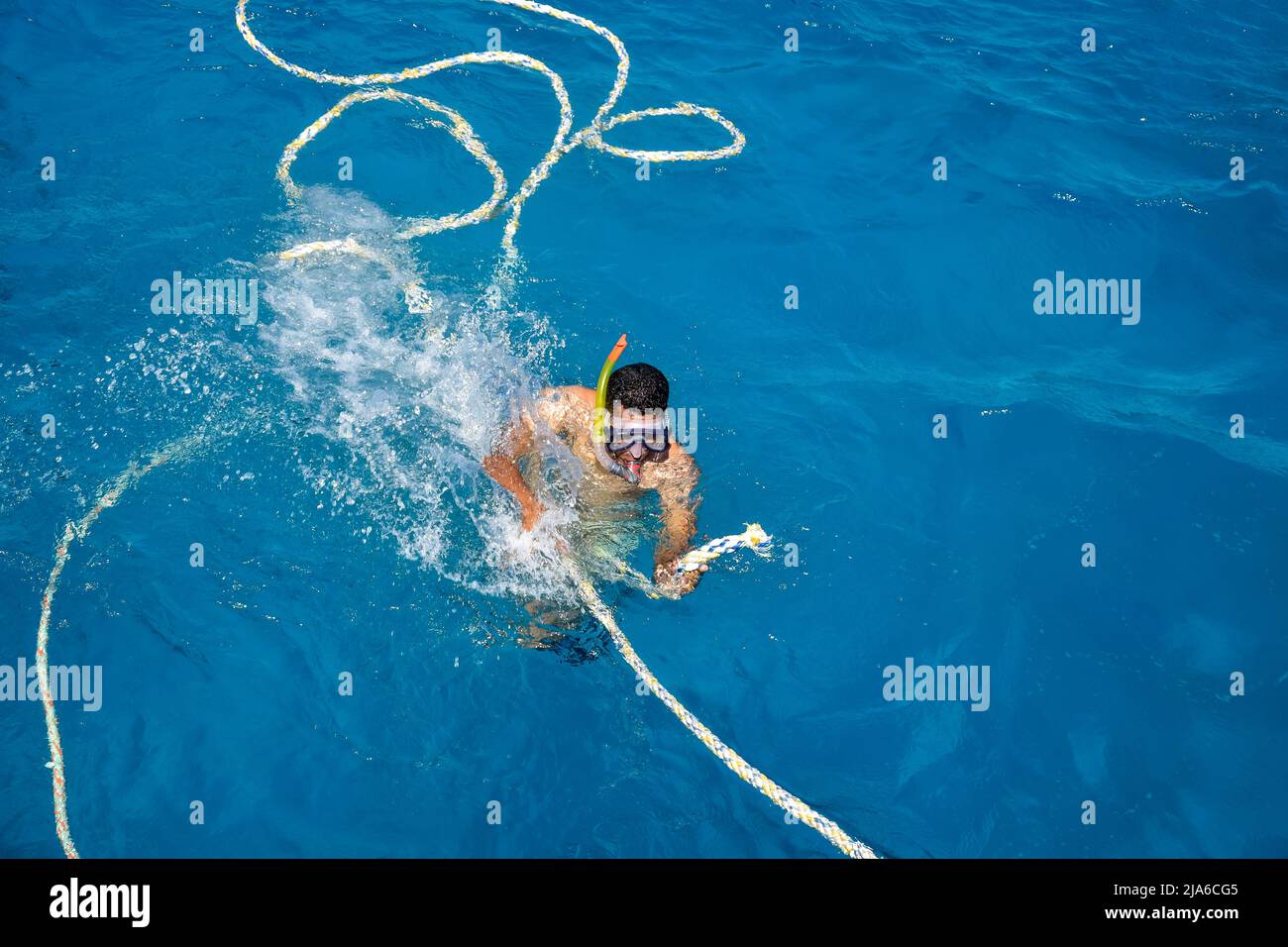 L'uomo africano è impegnato nello snorkeling. Un uomo in maschera e pinne nuota sul mare. Vista dall'alto. Hurghada, Egitto - Marzo 2022 Foto Stock