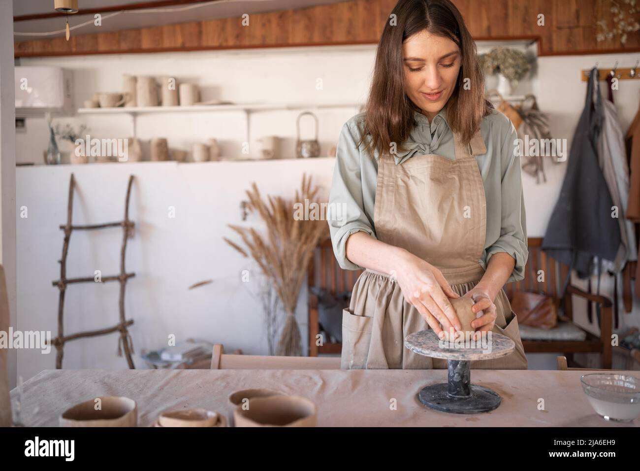 Ceramica caucasica femminile che lavora con argilla al volante di un vasaio in uno studio creativo professionale, artista femminile che crea ceramica artigianale artigianale. Rilassatevi Foto Stock